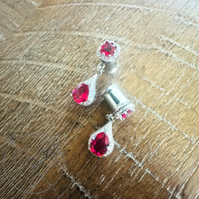 Load image into Gallery viewer, a pair of red gemstone earrings with a silver metal frame, placed on a wooden surface.