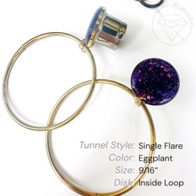Load image into Gallery viewer, a pair of gold hoop earrings with a single flared design and a small purple glittery accent. The earrings are placed on a white background, and there is a small black object in the top right corner.