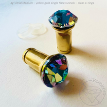Load image into Gallery viewer, two ornate, gold-colored objects with colorful, multicolored gemstones on them, placed on a white surface.