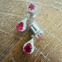 Load image into Gallery viewer, a pair of elegant earrings with red gemstones, displayed on a wooden surface.