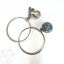 Load image into Gallery viewer, a pair of silver hoop earrings with colorful, glittery elements.