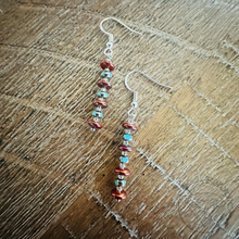 Load image into Gallery viewer, A pair of earrings with colorful beads hanging from the hooks, resting on a wooden surface.