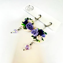 Load image into Gallery viewer, A pair of earrings with purple and white flowers, hanging from the ear hooks.