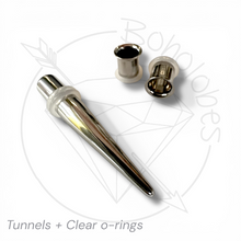 Load image into Gallery viewer, a pair of silver-colored metal piercing plugs, including a straight tube and two clear o-rings, arranged on a white background.
