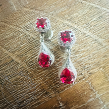 Load image into Gallery viewer, A pair of elegant earrings with red gemstones, likely rubies, set in a silver and white design.