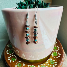 Load image into Gallery viewer, A pair of earrings with colorful beads hanging from them, placed in a pink ceramic pot with a plant growing in it.